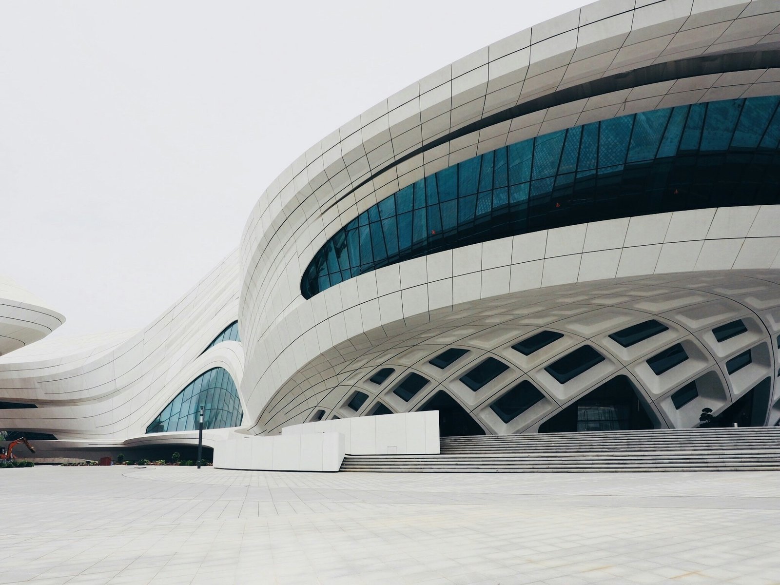 Edifício branco futurista com linhas curvas e grandes caixilhos geométricos.