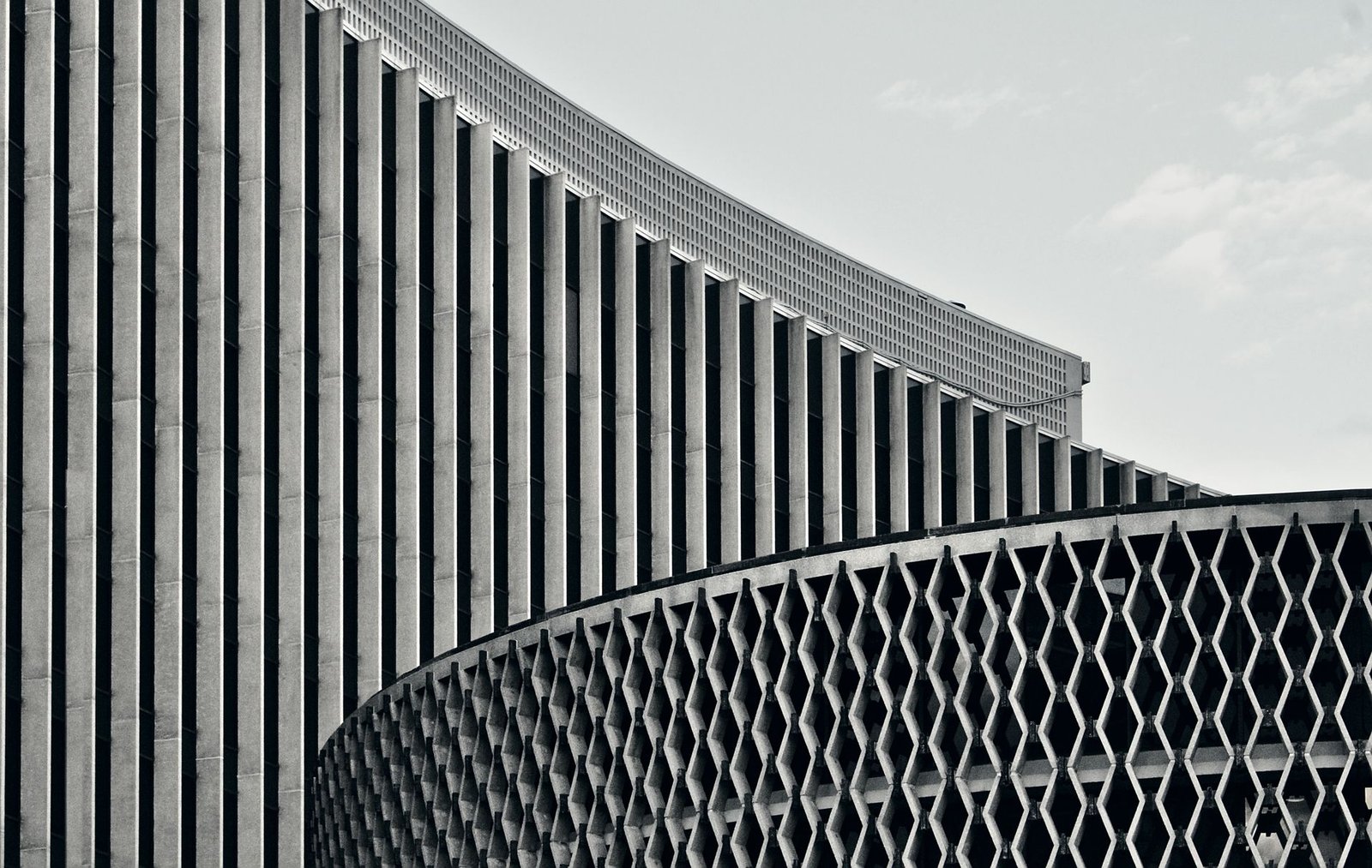 Fachada moderna com painéis verticais brancos listrados sobre malha geométrica em preto e branco.