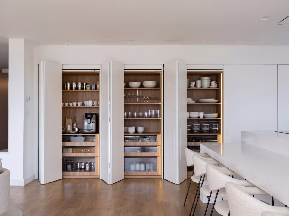 Três armários embutidos com louças e outros itens em uma cozinha.